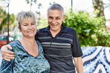 Naklejka premium Middle age caucasian couple of husband and wife together on a sunny day outdoors. Smiling happy in love hugging at the city.