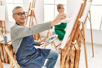Two middle age artist smiling happy painting at art studio.