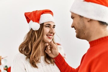 Young hispanic couple smiling happy wearing christmas hat at home.
