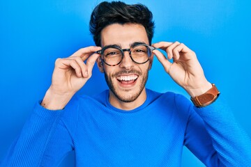 Young hispanic man wearing glasses smiling and laughing hard out loud because funny crazy joke.