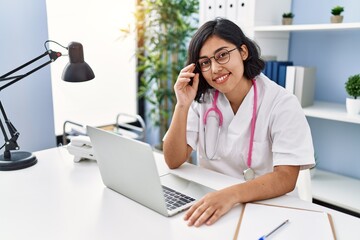 Young latin woman wearing doctor uniform working at clinic