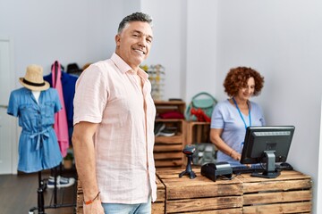 Fototapeta premium Middle age man and woman smiling confident shopping at clothing store