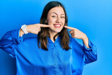 Young brunette woman wearing casual blue shirt smiling cheerful showing and pointing with fingers teeth and mouth. dental health concept.