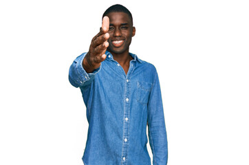 Young african american man wearing casual clothes smiling friendly offering handshake as greeting and welcoming. successful business.