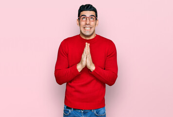 Handsome hispanic man wearing casual clothes and glasses begging and praying with hands together with hope expression on face very emotional and worried. begging.