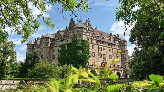View of Neuenstein Castle framed by leaves in summer.