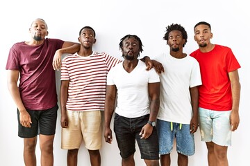 Obraz premium Young african group of friends standing together over isolated background making fish face with lips, crazy and comical gesture. funny expression.
