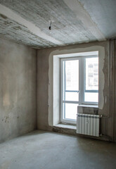 Unfinished building. Rough finish of the apartment. Room with plastered concrete walls.