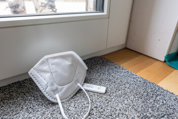 High angle view of positive self test and protective mask on the floor and boots of person behind...