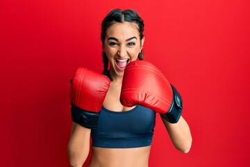 Young brunette girl using boxing gloves celebrating crazy and amazed for success with open eyes...