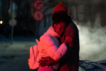 Affectionate african american couple hugging at dark street saying good bye to each other. Man and woman in love embrace outdoor express sincere feelings and sadness. Farewell and relationship concept
