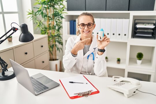 Young doctor woman wearing uniform and stethoscope smiling happy pointing with hand and finger