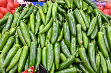 Green chili peppers. Fresh peppers for sale at vegetable market, close up. Boxes full of chili paprika in shop. Chili at the greengrocer's stall. Vegetable. 