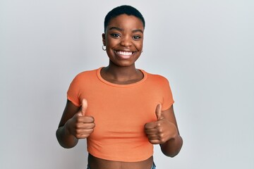 Young african american woman wearing casual orange t shirt success sign doing positive gesture with hand, thumbs up smiling and happy. cheerful expression and winner gesture.