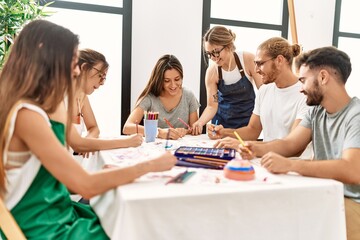 Obraz premium Group of young paint students smiling happy and drawing sitting on the table at art studio.