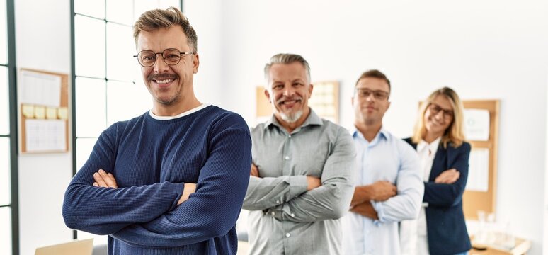 Group of middle age business workers smiling happy standing with arms crossed gesture at the office.