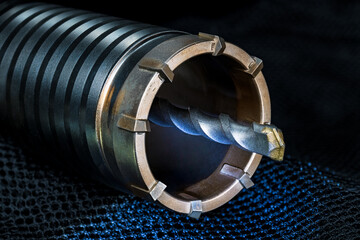 Detail of hole saw cutter with spiral pilot drill bit on blue net with black background. Closeup a...
