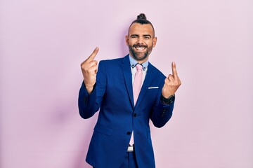 Young hispanic man wearing business suit and tie showing middle finger doing fuck you bad expression, provocation and rude attitude. screaming excited