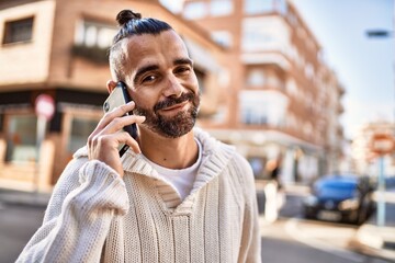 Handsome middle age man with beard standing happy and confident outdoors having a conversation speaking on the phone