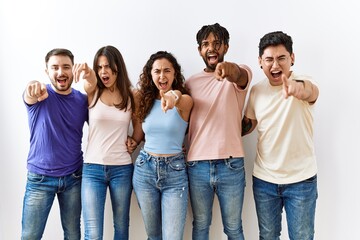 Obraz premium Group of young people standing together over isolated background pointing displeased and frustrated to the camera, angry and furious with you