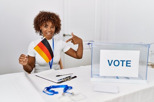 Young african american woman at political campaign election holding germany flag pointing finger to one self smiling happy and proud