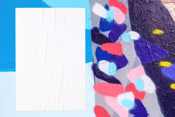 Closeup of colorful black pink blue painted urban wall texture with wrinkled glued poster template....