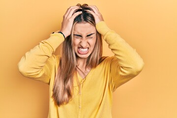 Beautiful hispanic woman wearing casual yellow sweater suffering from headache desperate and stressed because pain and migraine. hands on head.