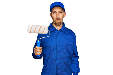 Bald man with beard holding roller painter thinking attitude and sober expression looking self confident