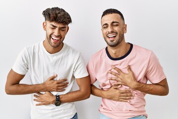 Young gay couple standing over isolated background smiling and laughing hard out loud because funny...