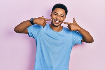 Young african american man wearing casual blue t shirt smiling cheerful showing and pointing with...