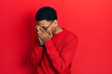 Young african american man wearing casual clothes and glasses with sad expression covering face with hands while crying. depression concept.