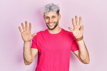 Young hispanic man with modern dyed hair wearing casual pink t shirt showing and pointing up with...