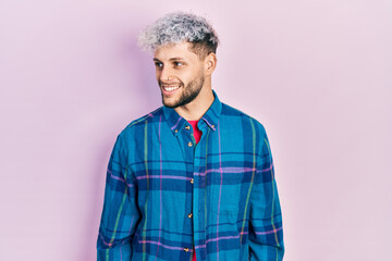 Young hispanic man with modern dyed hair wearing casual retro shirt looking to side, relax profile pose with natural face and confident smile.