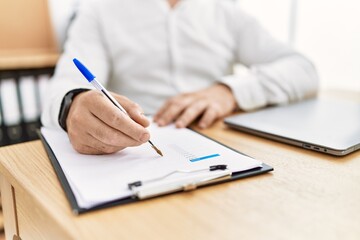Businessman writing on clipboard at the office.