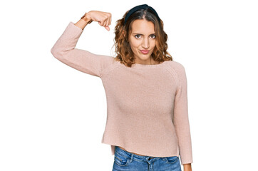 Obraz premium Beautiful young caucasian woman wearing casual sweater strong person showing arm muscle, confident and proud of power