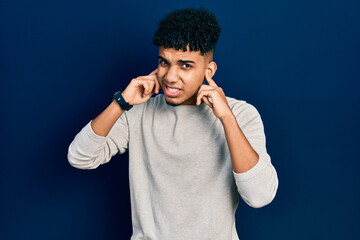 Young african american man wearing casual clothes covering ears with fingers with annoyed expression for the noise of loud music. deaf concept.