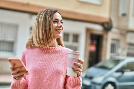 Young caucasian girl using smartphone and drinking coffee at the city.