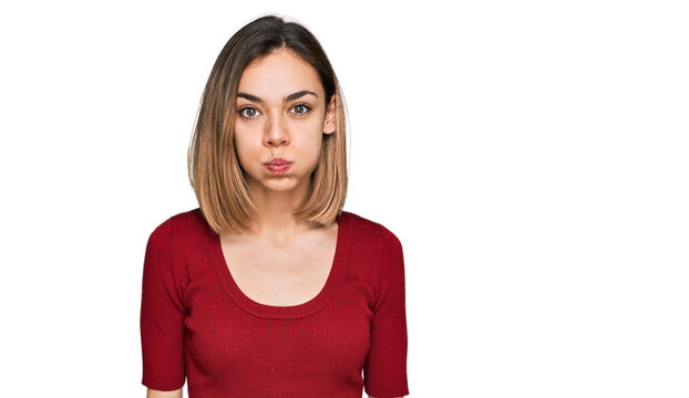 Young blonde girl wearing casual clothes puffing cheeks with funny face. mouth inflated with air, crazy expression.