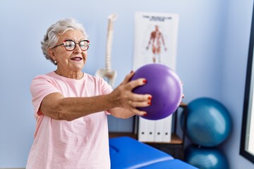 Senior grey-haired woman physitherapist patient having rehab session using ball at physitherapy...