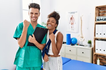 Physiotherapist working with patient wearing arm on sling at rehabilitation clinic very happy and...