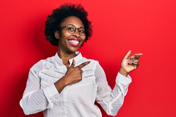 Young african american woman wearing casual clothes and glasses smiling and looking at the camera pointing with two hands and fingers to the side.