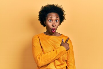 Obraz na płótnie Canvas Young african american woman wearing casual clothes surprised pointing with finger to the side, open mouth amazed expression.