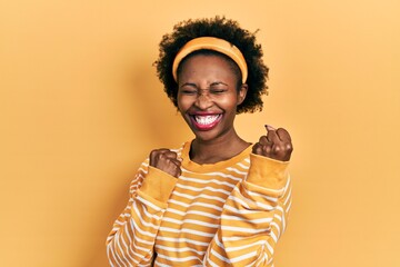 Young african american woman wearing casual sweatshirt celebrating surprised and amazed for success with arms raised and eyes closed