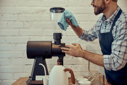 Male bartender cleaning coffee machine in cafe