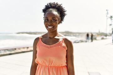Young african american woman smiling happy on a summer day by the beach
