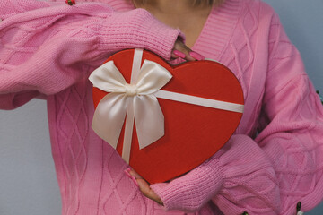 Girl holding a gift in the shape of a heart. The concept of the holiday, Valentine's Day, birthday, women's day, 14 February.
