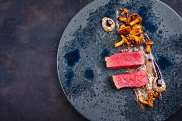 Modern Style traditionelles gebratenes dry aged Angus Rinderfilet mit Pfifferling Mousse Parfait und Wildkirsch Relish Creme serviert als Draufsicht auf einem Nordic Design Teller mit Textfreiraum © HLPhoto