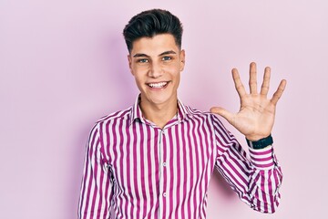Naklejka premium Young hispanic man wearing casual clothes showing and pointing up with fingers number five while smiling confident and happy.