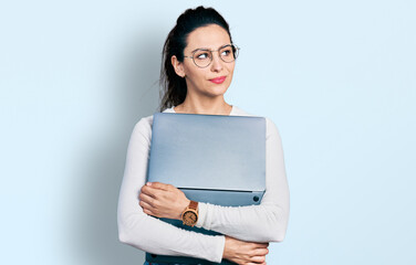 Young hispanic woman working using computer laptop smiling looking to the side and staring away thinking.