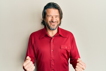 Obraz premium Middle age handsome man wearing casual clothes very happy and excited doing winner gesture with arms raised, smiling and screaming for success. celebration concept.